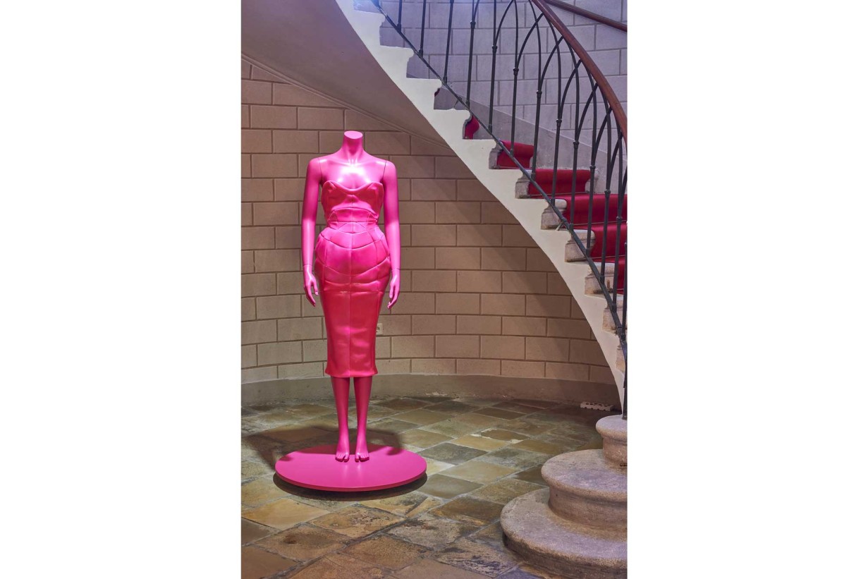 A Biedermeier style room with a mannequin wearing a pink fashion design. 