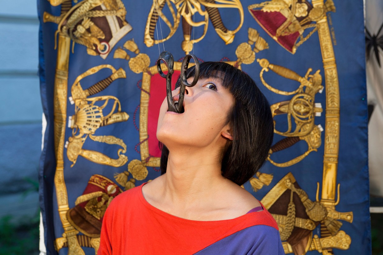 Eine Person mit geöffnetem Mund ist dabei eine Schere zu verschlucken