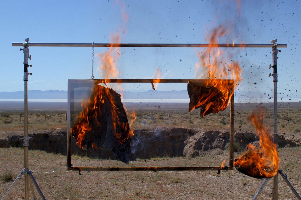 A canvas goes up in flames in a desert landscape