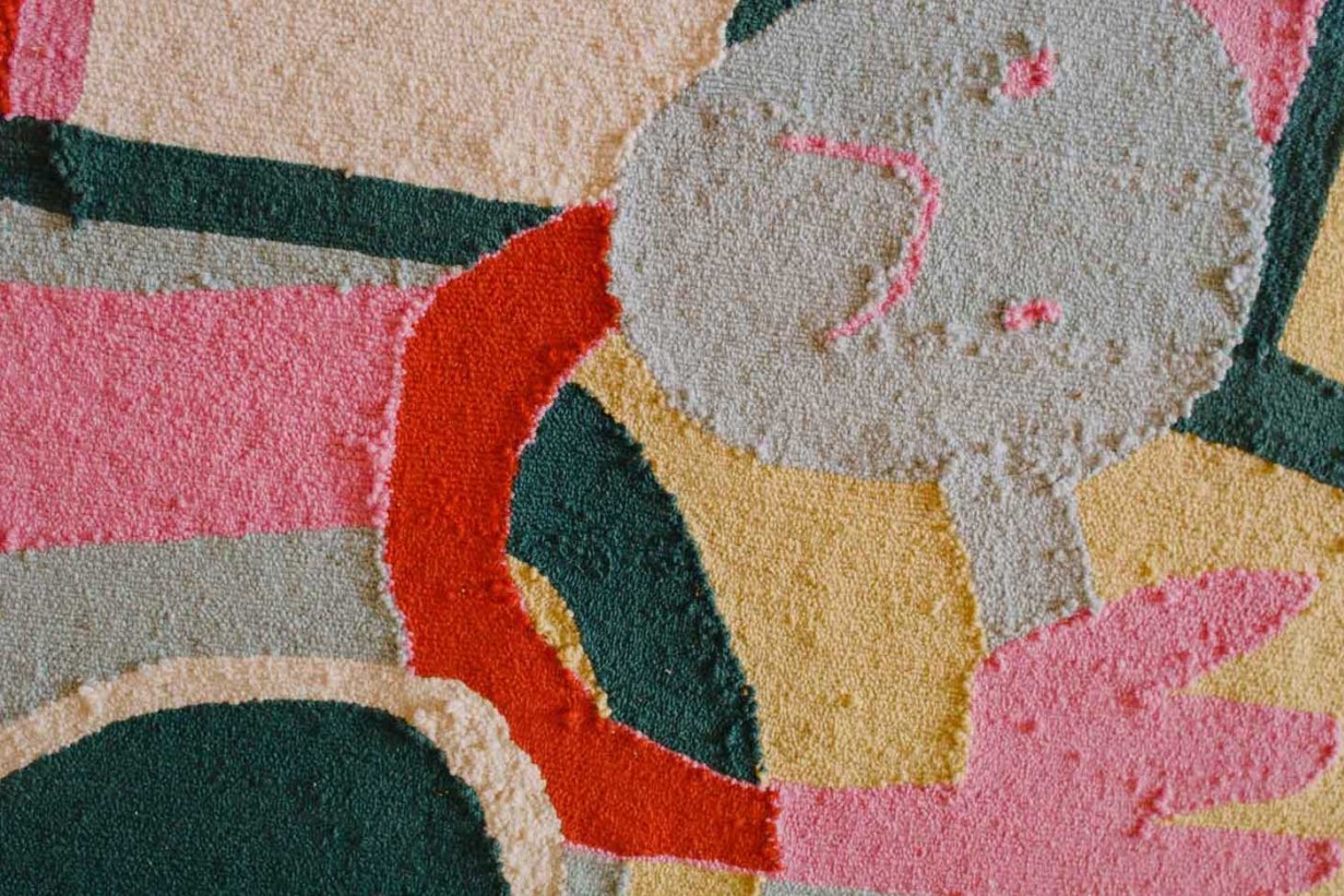 Detailausschnitt eines getuffteten Teppichs mit verschiedenen Farben.