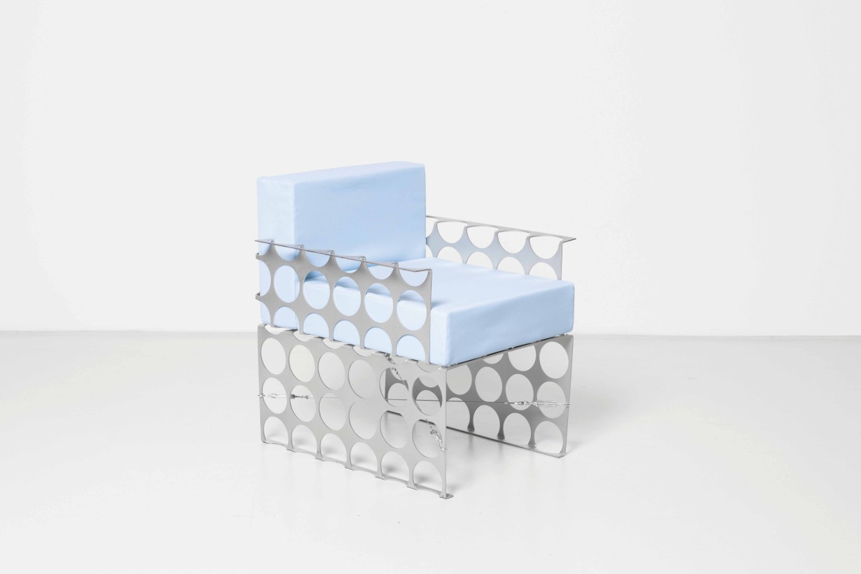 Ein Stuhl aus Metall mit blauem Kissen.